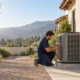 Licensed technician from an HVAC company in Glendale checking a new AC condenser beside a stucco home
